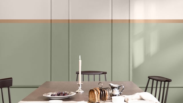 Dining table setting with a lit white candle, plates, and glass pitcher in a calm, sage-colored room