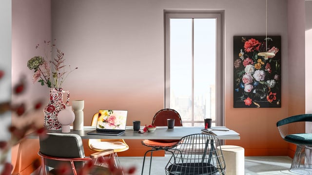 Bright home office with desk, laptop, flowers in vases and framed wall art