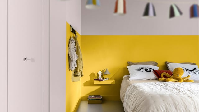Bedroom with a bold yellow accent wall, neatly made bed, and cute animal-themed pillows.