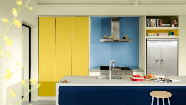 Modern kitchen with blue cabinets, yellow doors, and a stove on the kitchen island.