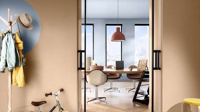 Bright interior view with coat hooks, bicycle, and a modern office beyond a doorway with pendant lights