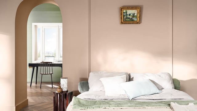 Modern bedroom with arched doorway, made bed in soft sage and white tones, and a glimpse of a dining table