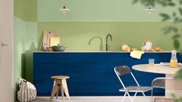 Modern kitchen with dark blue cabinets, light walls, and a dining table with chairs.