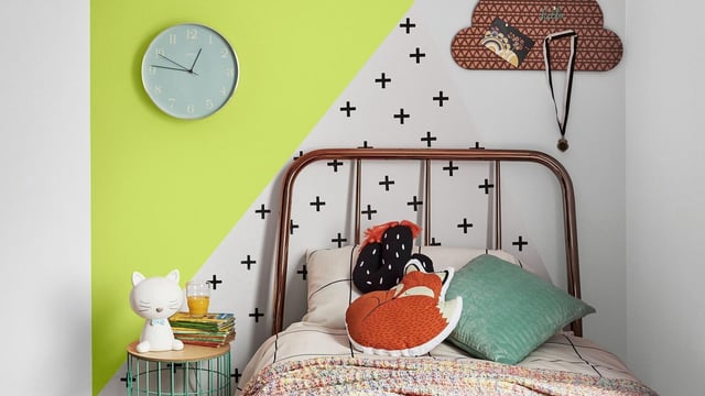 Kids room with a bed, cat bedside lamp, wall clock, and colourful geometric wall decals
