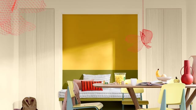 Bright room with a bold yellow wall, bed, and a desk with books and décor.