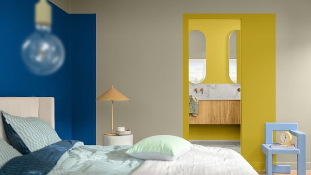 Bedroom with blue accent wall, bed with pillows, and a yellow niche with an arched mirror.