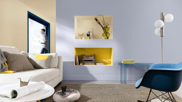 Modern living room with a blue armchair, yellow wall shelves and a grey sofa.