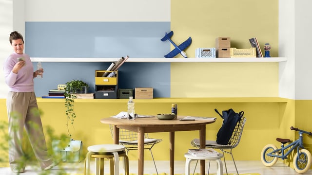Bright home office with blue and yellow walls, desk, chairs, shelves and a bicycle in the corner