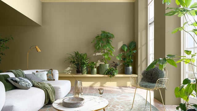 Bright living room with a white sofa, marble coffee table, and many potted plants by the windows.