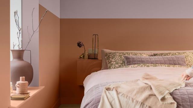 Warm bedroom with a bed, pillows, and a bedside table with decorative items