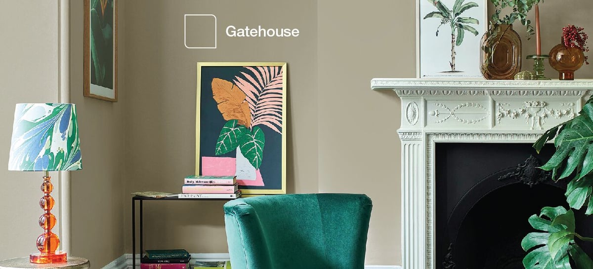 Living room interior with teal chair, framed art, table lamp, fireplace mantle and plants; “Gatehouse” sign