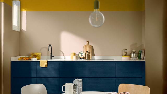 Bright kitchen with blue cabinets, sink, countertop and warm yellow walls.